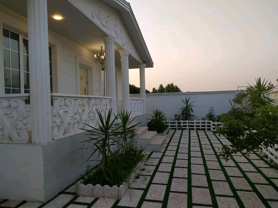 تصویر یک ویلای فلت روستایی که محوطه سازی شده و از چمن مصنوعی استفاده شده