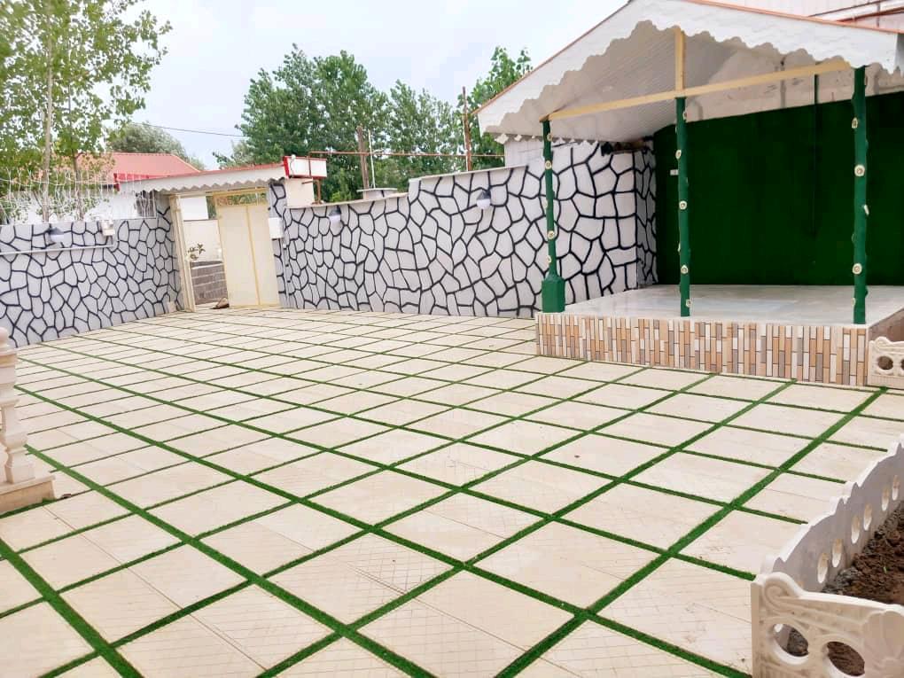 تصویر یک ویلای فلت روستایی که محوطه سازی شده و از چمن مصنوعی استفاده شده