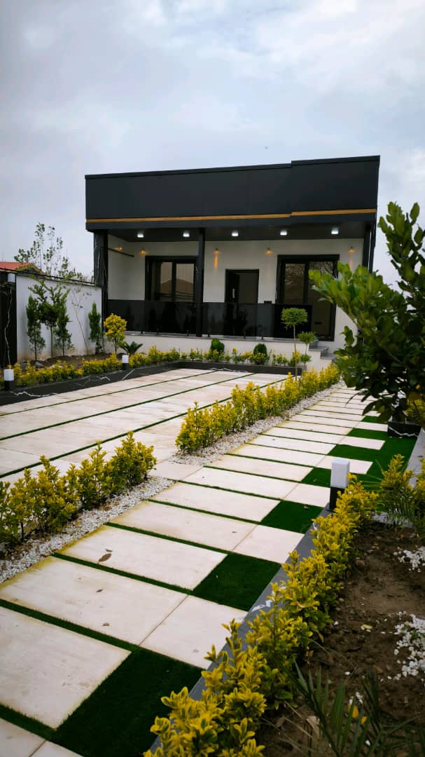 تصویر یک ویلای نما مدرن و محوطه سازی شده با موزاییک و چمن مصنوعی