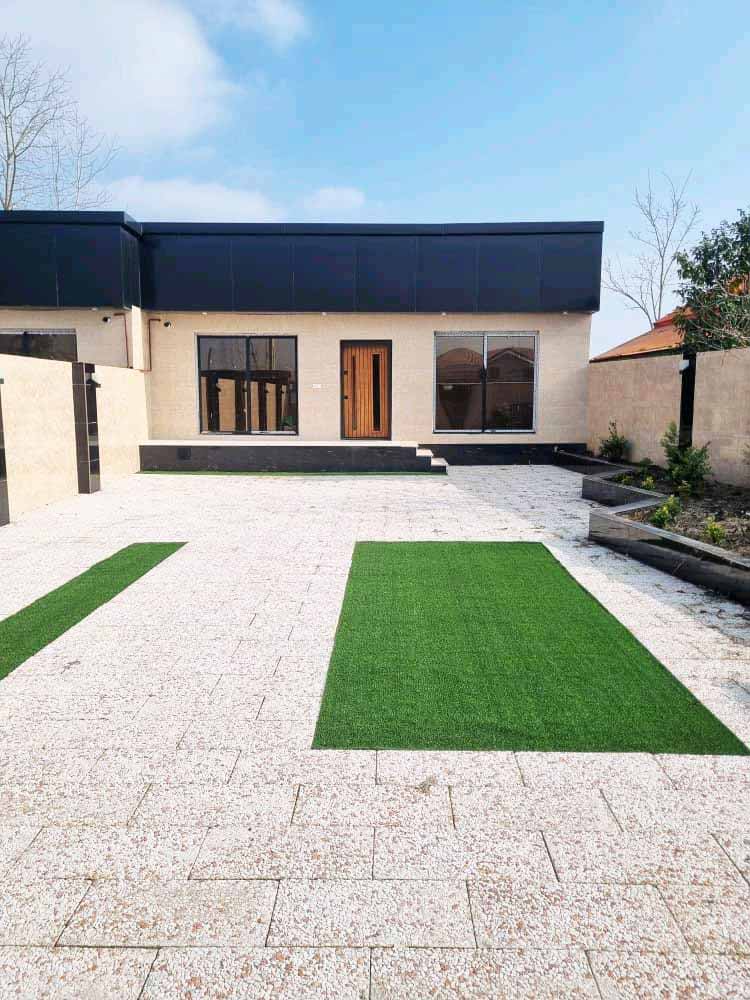تصویر یک ویلای فلت روستایی که محوطه سازی شده و از چمن مصنوعی استفاده شده