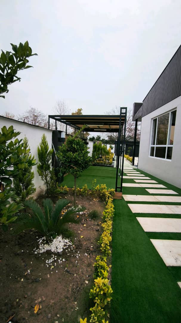 تصویر یک ویلای نما مدرن و محوطه سازی شده با موزاییک و چمن مصنوعی